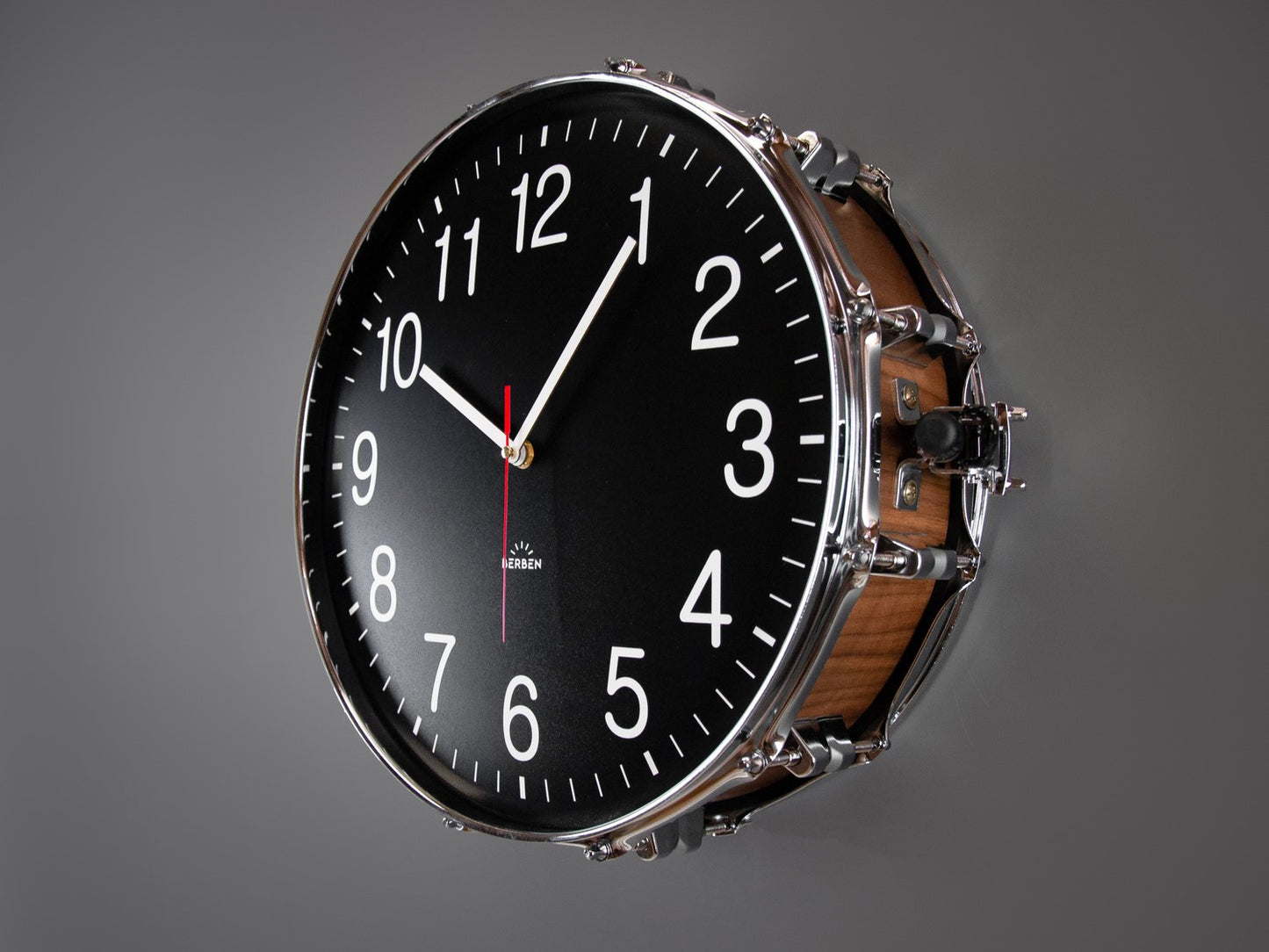 A clock made from a drum with a black clock face. The shell is finished with a rich walnut veneer.