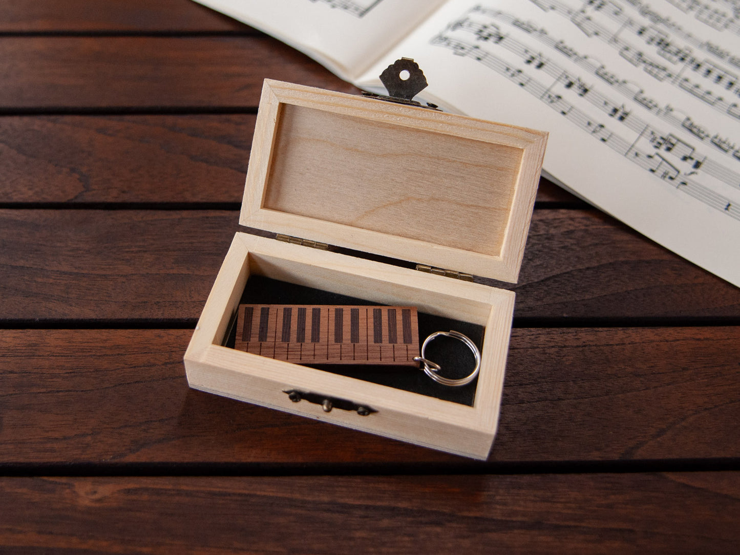 A piano shaped keychain placed inside a compact wooden box