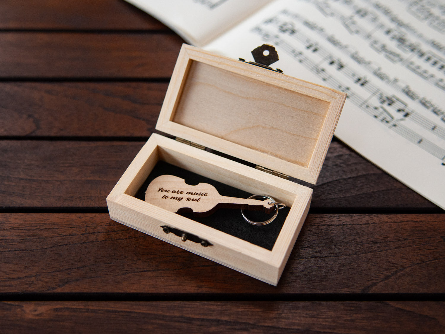 A keychain in the shape of a double bass stored in a small wooden box, featuring custom engraving