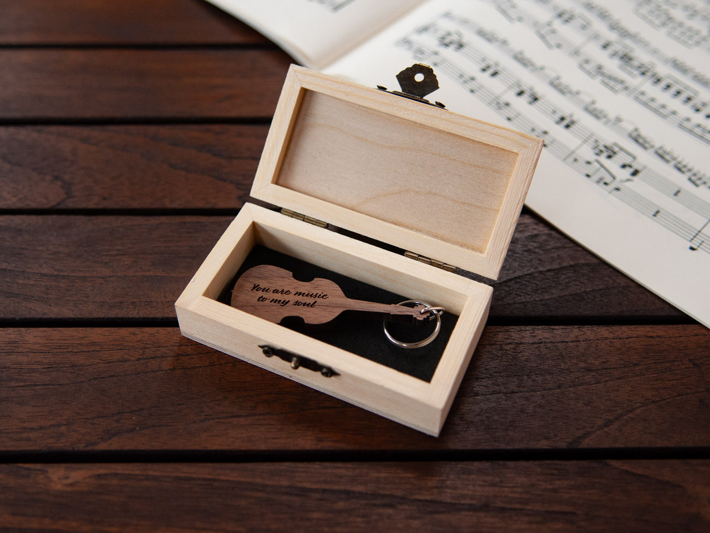 A keychain in the shape of a double bass stored in a small wooden box, featuring custom engraving