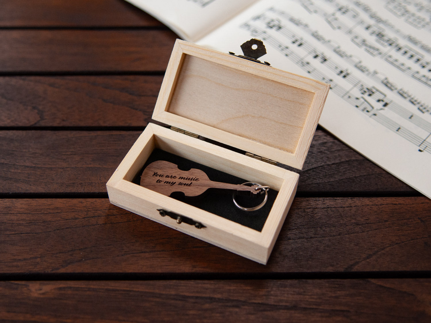 A keychain in the shape of a double bass stored in a small wooden box, featuring custom engraving