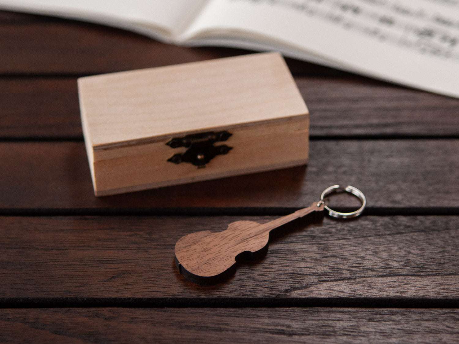 A keychain in the shape of a double bass in front of a small wooden box