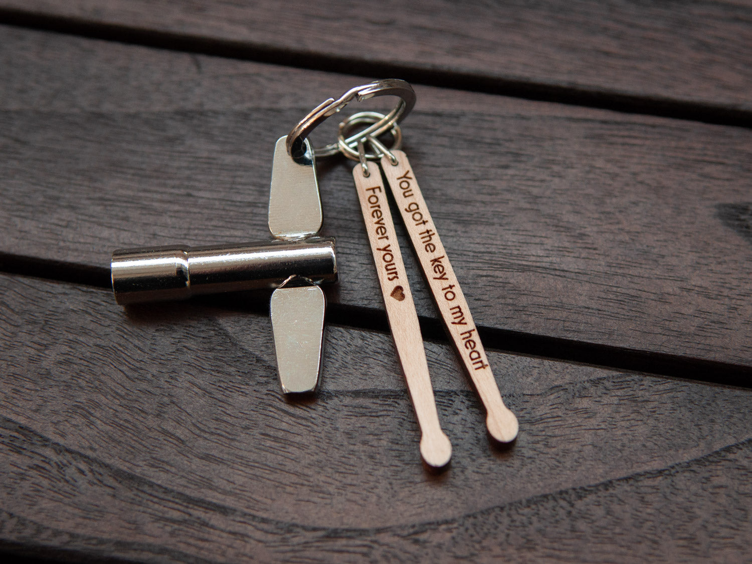 Keychain in the shape of drumsticks with personalized engraving, made from maple wood. A drum key is also attached to the key ring.