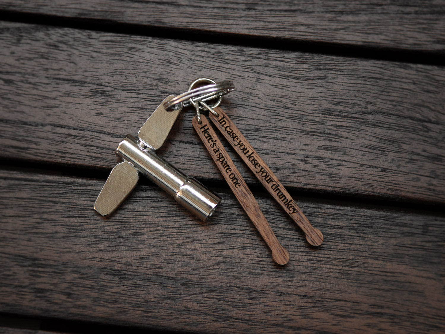 Keychain in the shape of drumsticks with engraving, made from walnut wood. A drum key is also attached to the key ring.