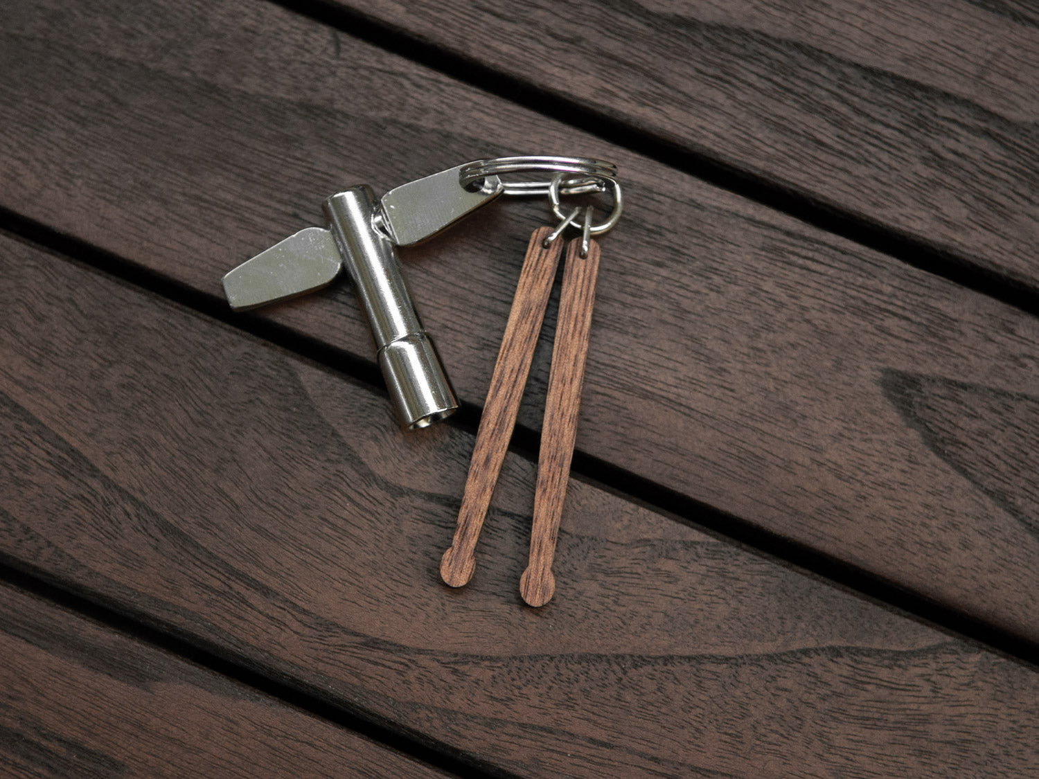 Keychain in the shape of drumsticks made from walnut wood. A drum key is also attached to the key ring.